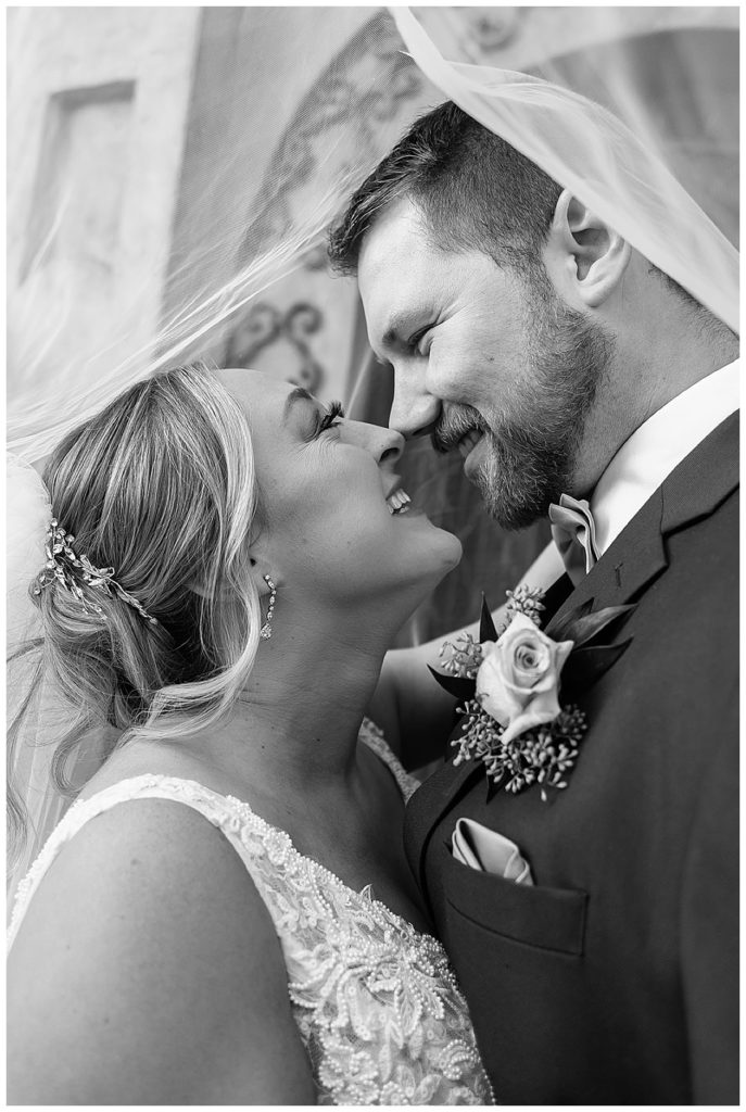 Couple smiles together under veil for Detroit Wedding Photographer