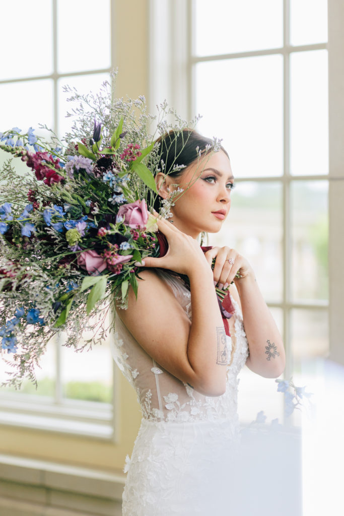 bride holding bouquet by ear in editorial pose for Kayla Bouren Photography