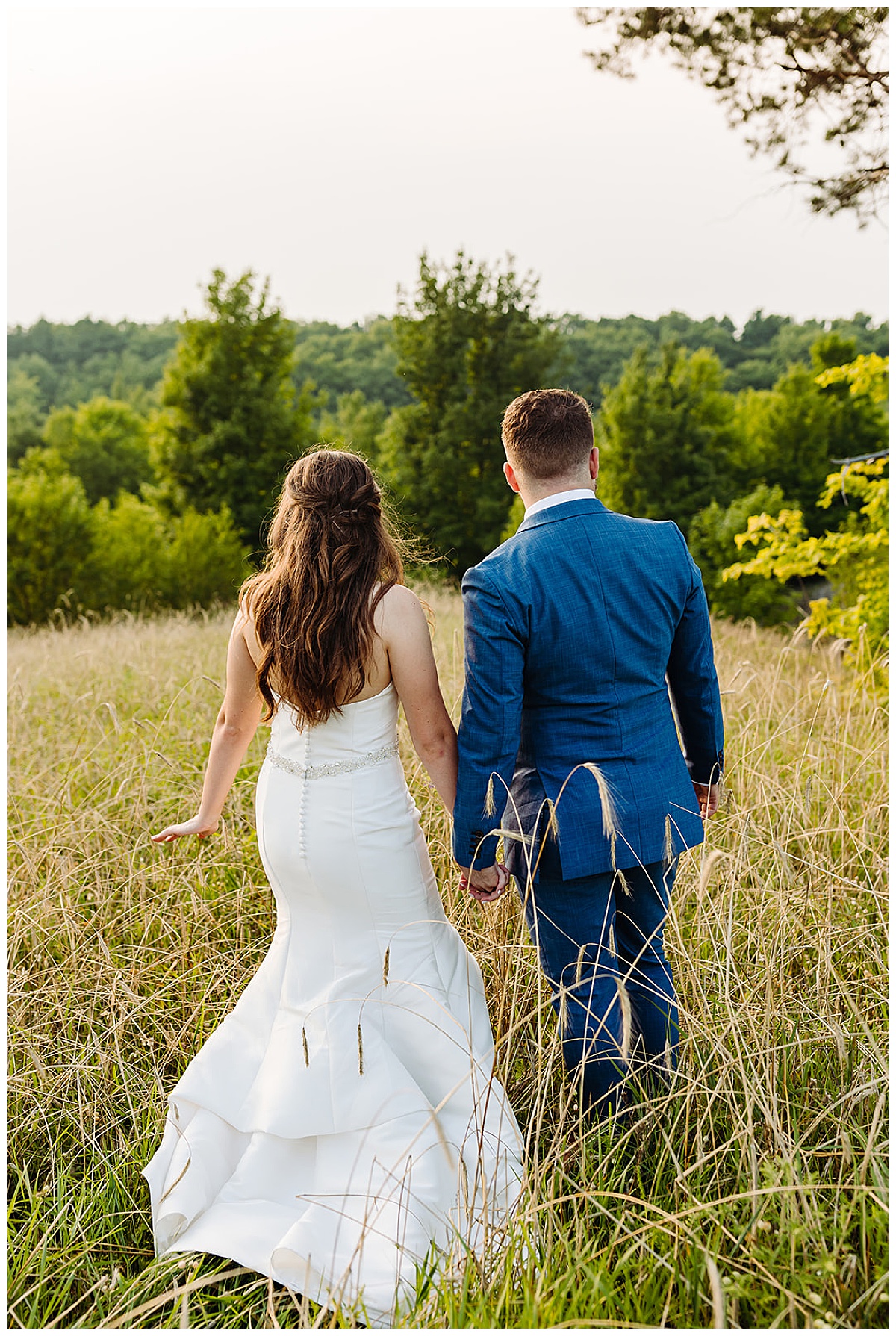 Couple walk together in field for Kayla Bouren Photography