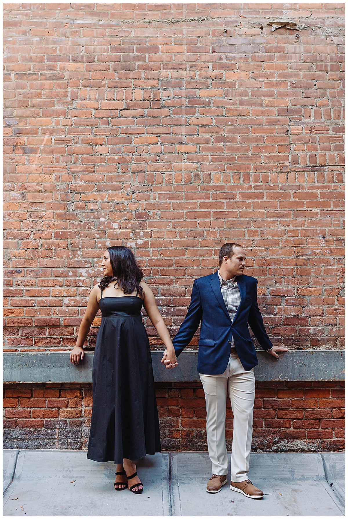 Bride and groom holds hands in front of wall during Woodward Ave. engagement session