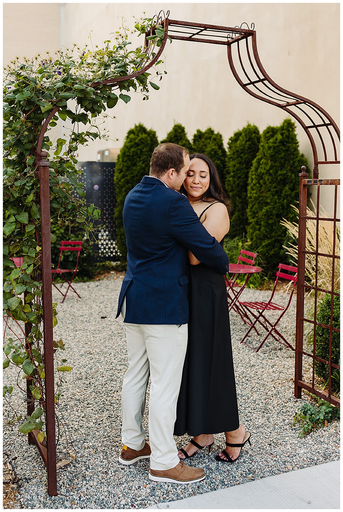 Couple hugs under flower arch for Kayla Bouren Photography