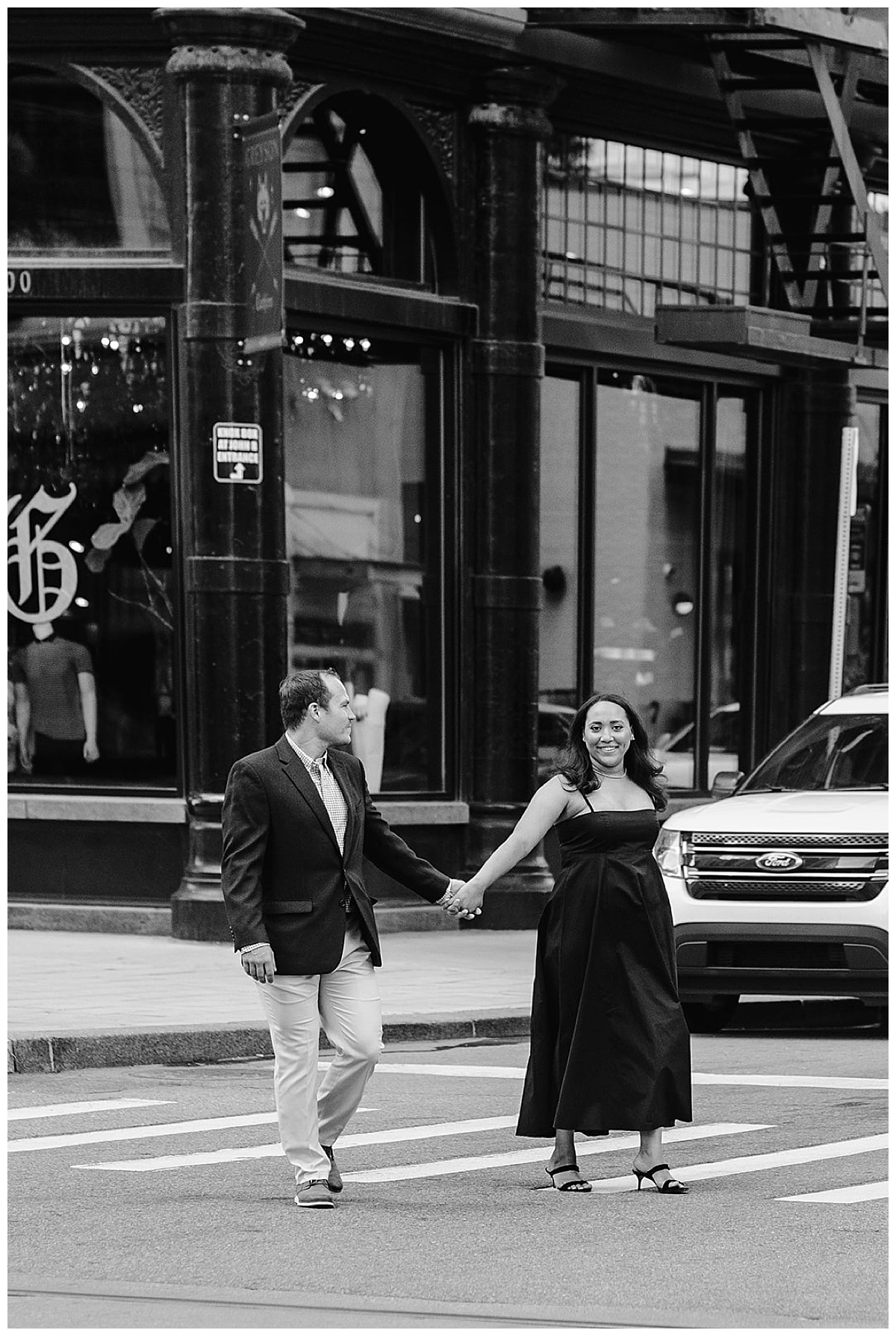 Two people walk hand in hand in the street for Woodward Ave. engagement session