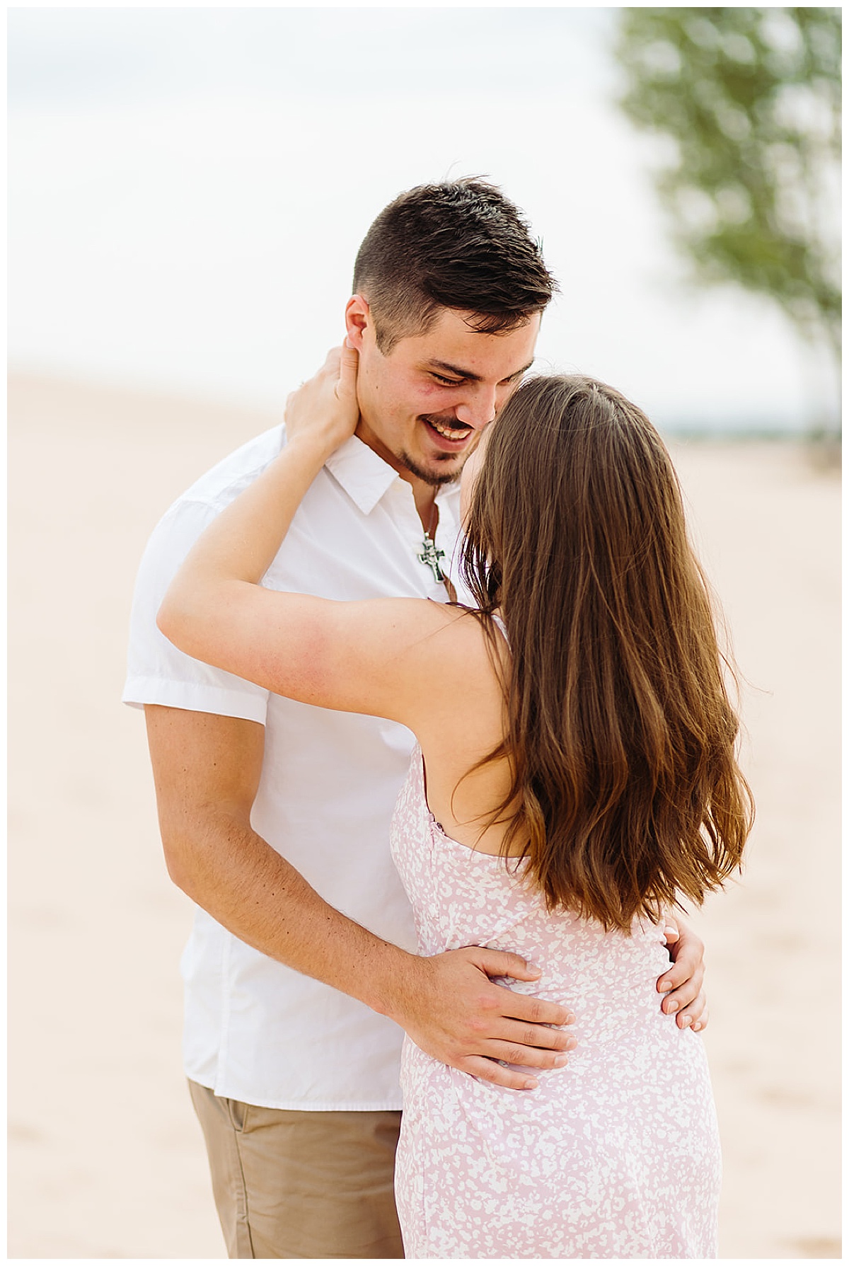 Two people smile up at one another for Mears, MI Engagement session
