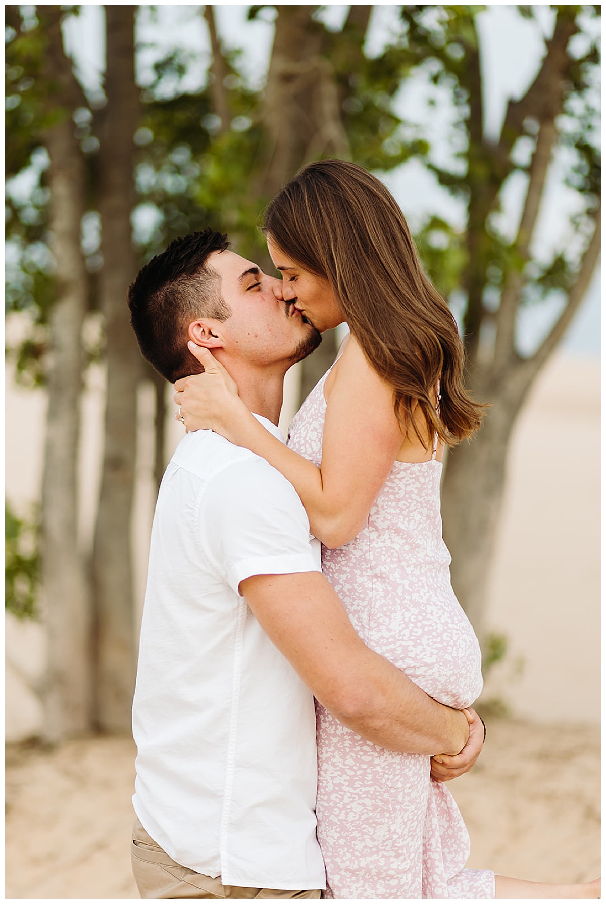 Engaged couple kiss by a tree for Kayla Bouren Photography