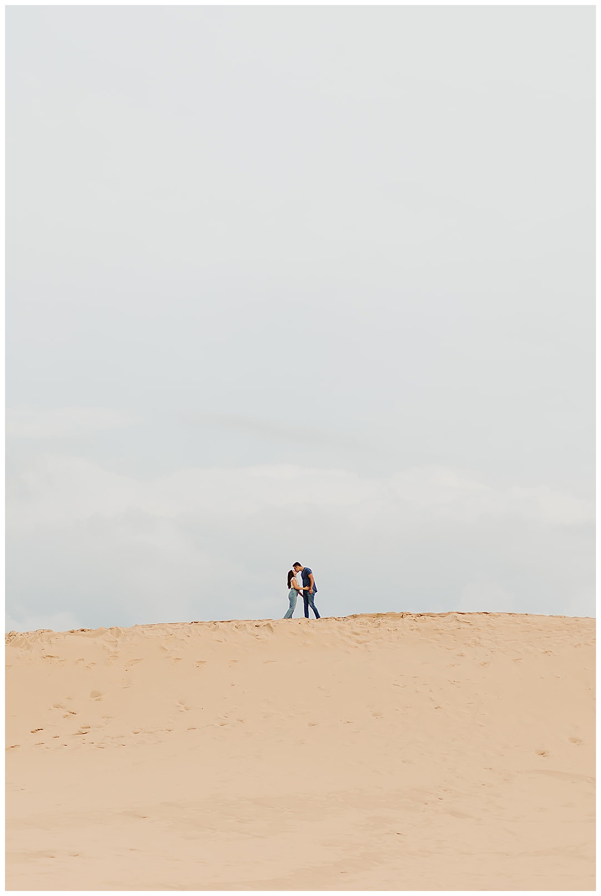 Two people kiss on top of sandy hill for Detroit Wedding Photographer