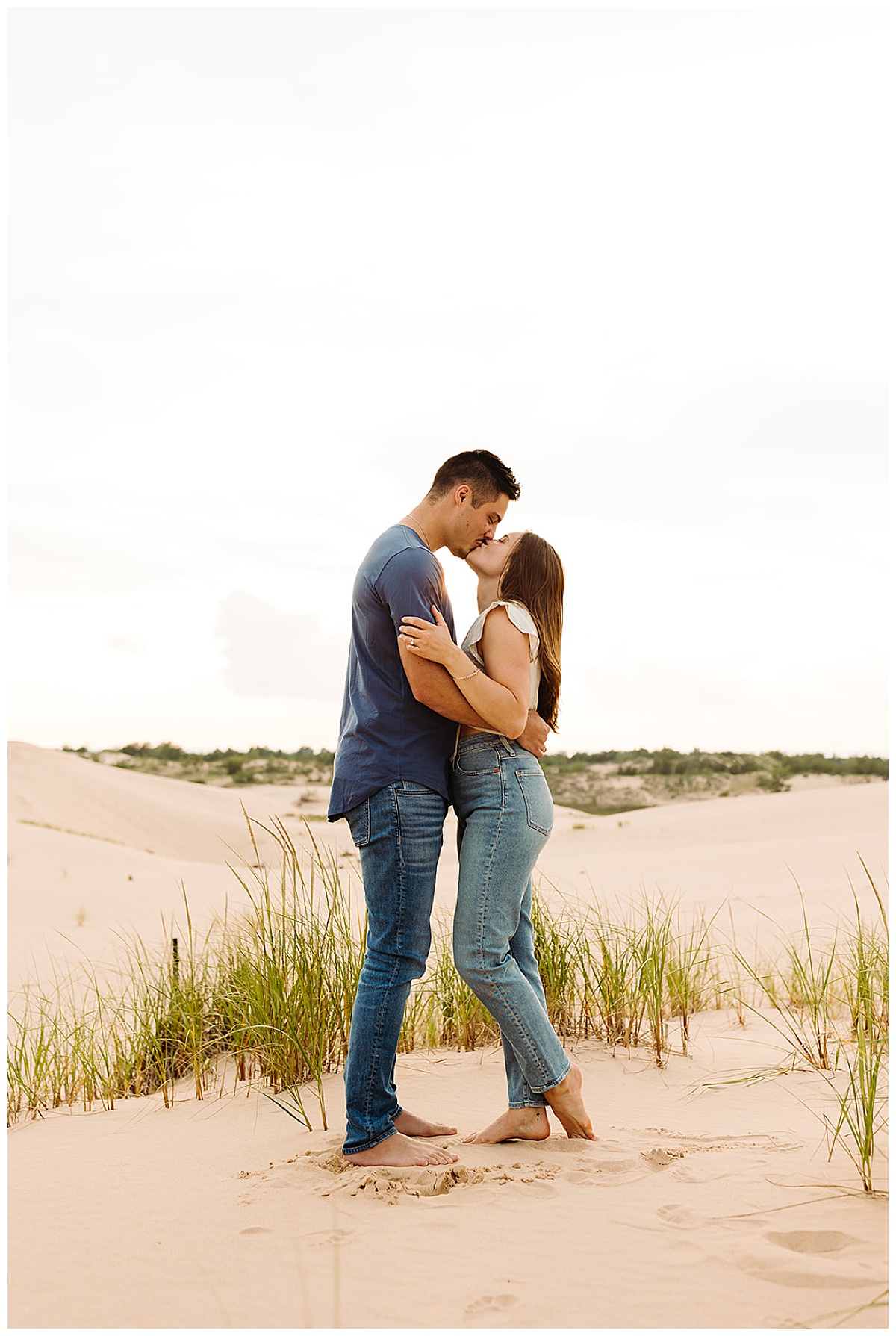 Woman looks up at man with a kiss during Mears, MI Engagement session