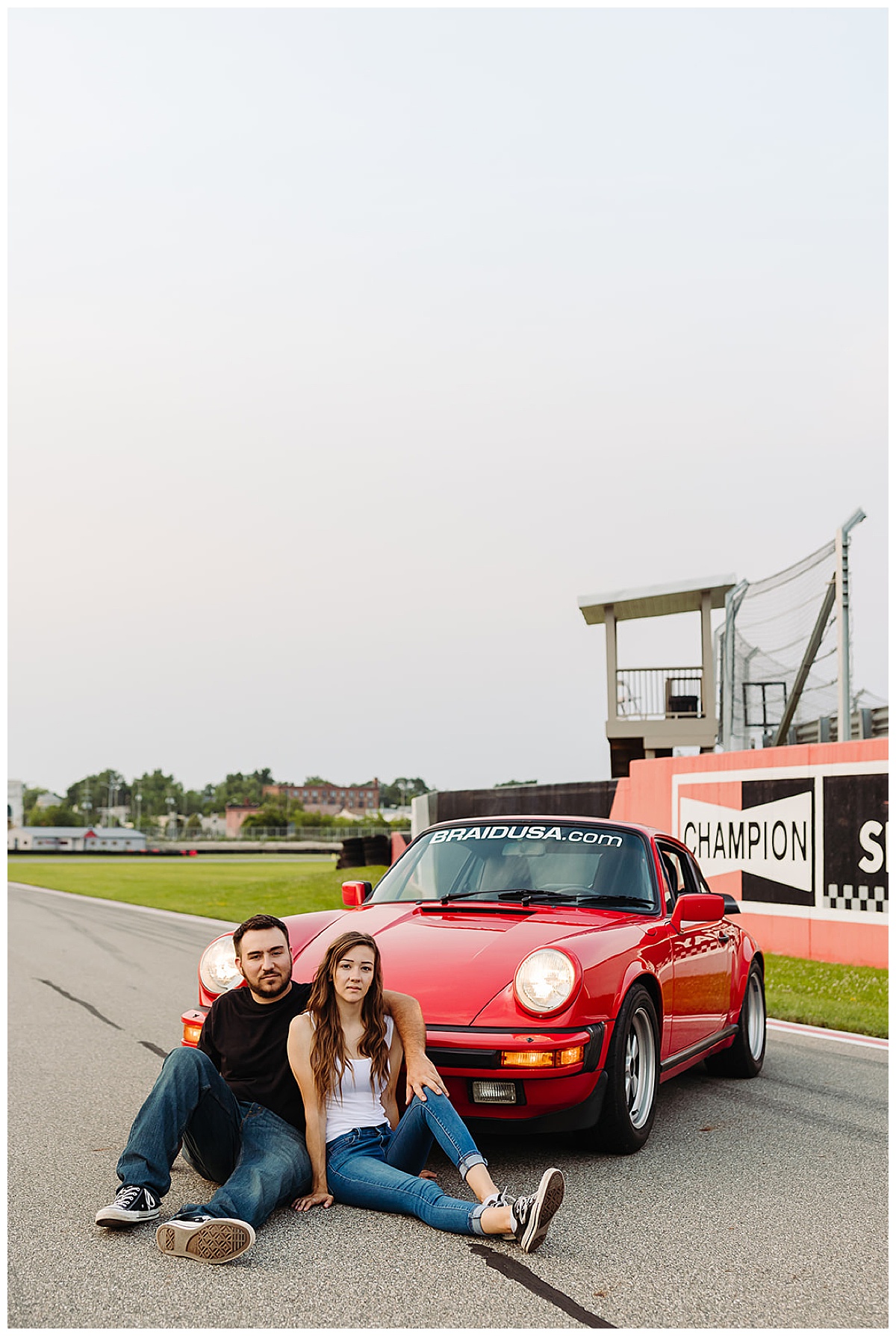 Couple sits in front of red Porsche for Detroit Wedding Photographer