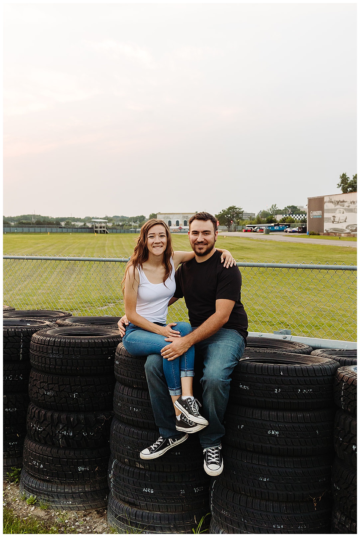 Future husband and wife sit on tire stack for Kayla Bouren Photography