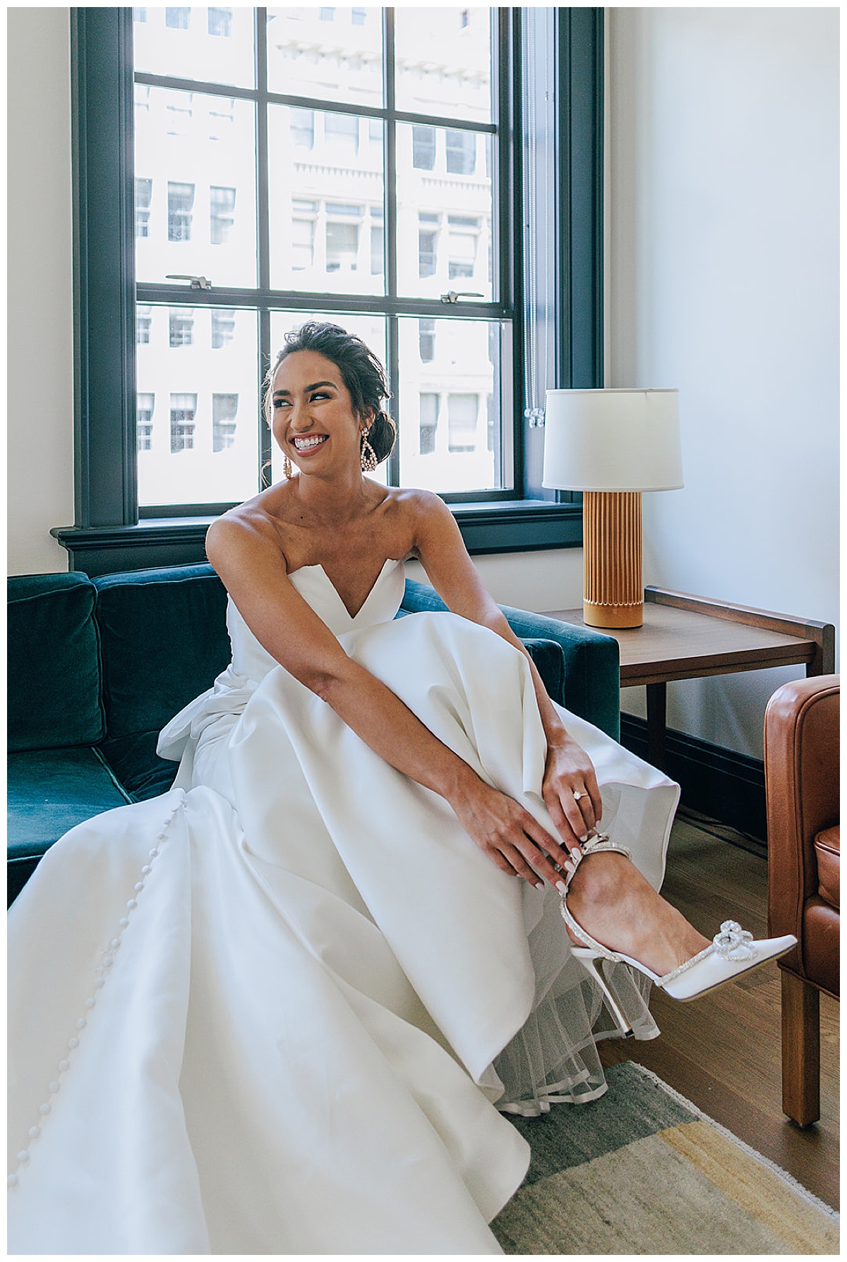 Bride smiles big as she puts on her wedding shoes for Detroit Wedding Photographer