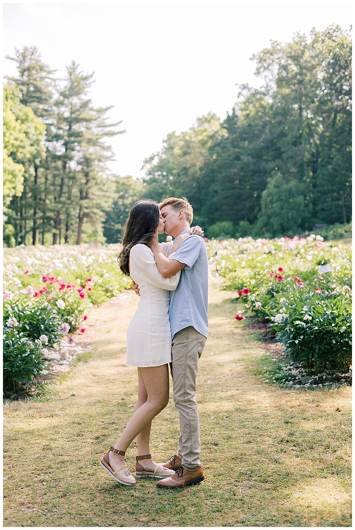Man and woman share a kiss during Ann Arbor peony garden engagement session