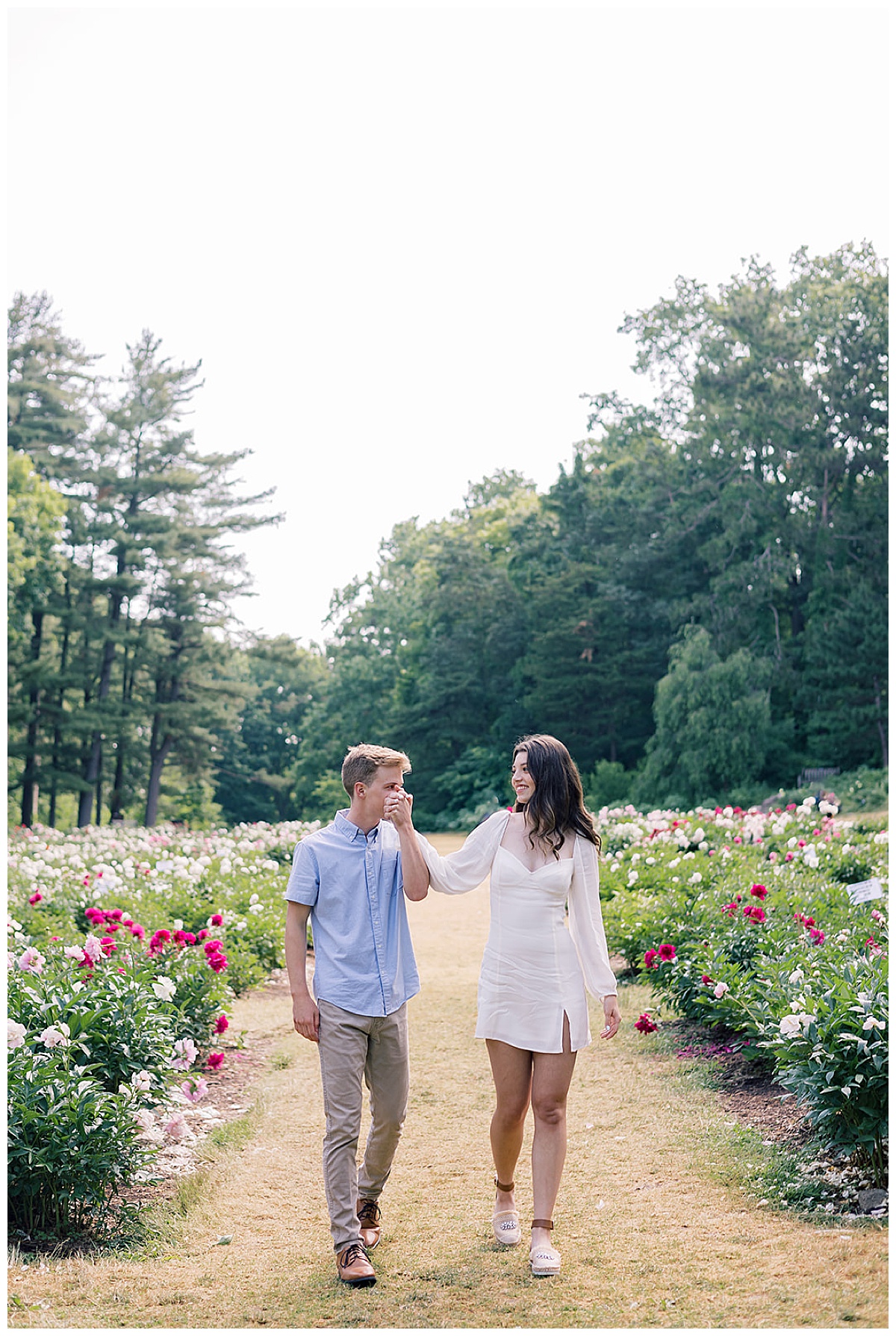 Future husband and wife walk hand in hand during Ann Arbor peony garden engagement session