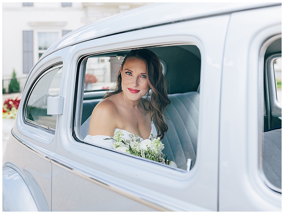Bride smiles in vintage car for Kayla Bouren Photography