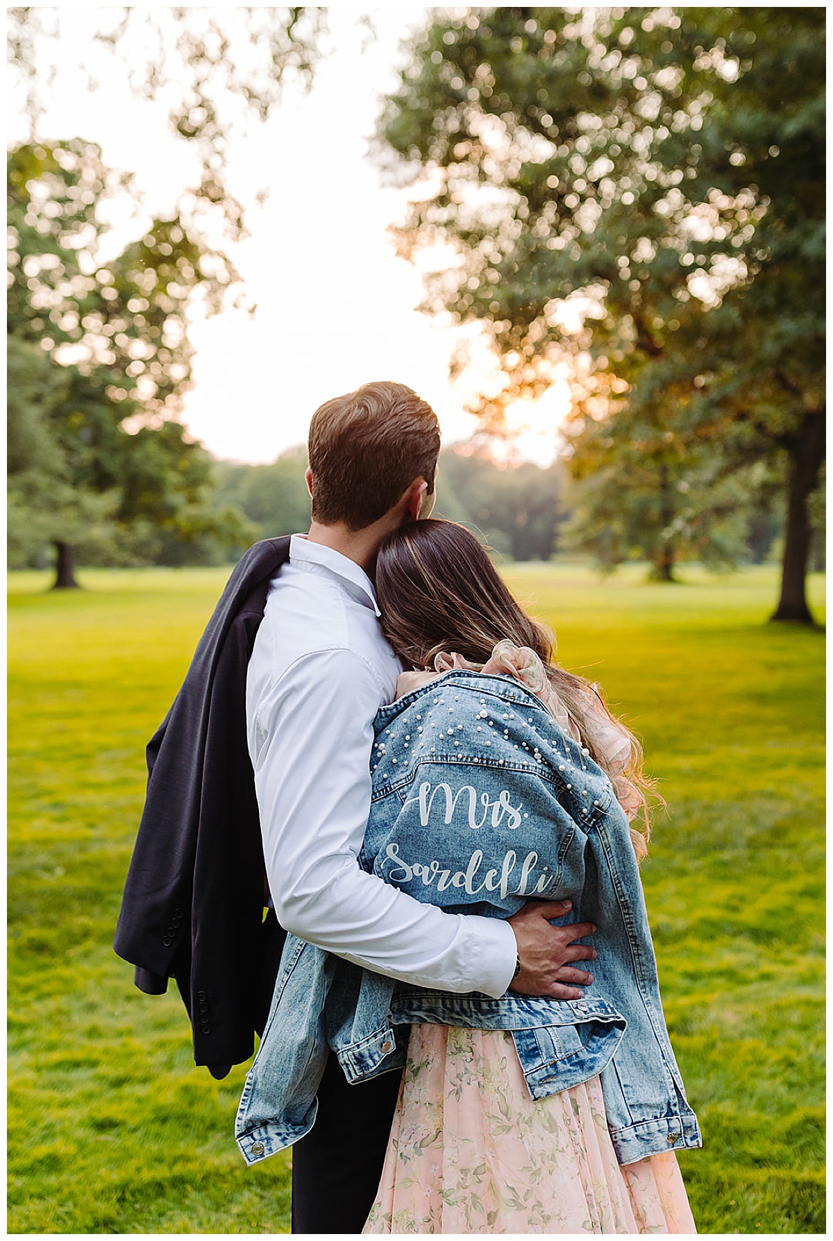 Man holds woman close wearing a custom bridal jean jacket at one of the estate engagement session locations in Michigan