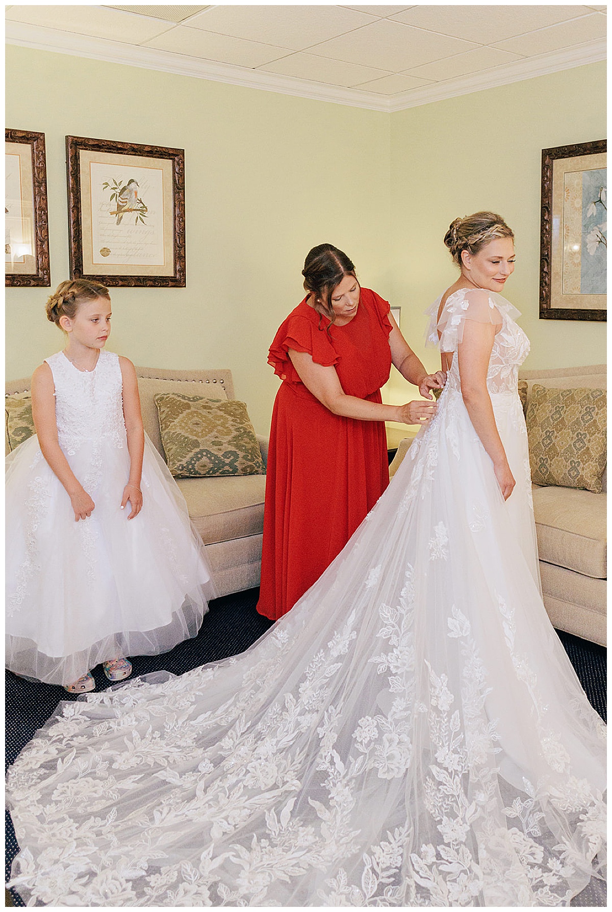 Family and friends help bride into her dress for Kayla Bouren Photography