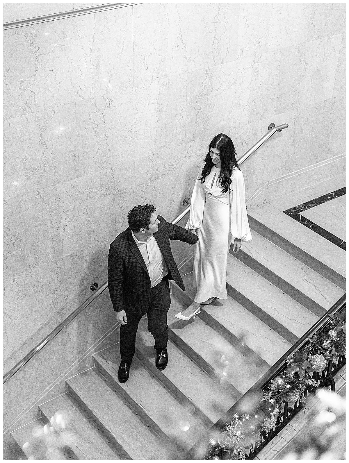 Man leads woman down the stairs during their Detroit Athletic Club engagement session