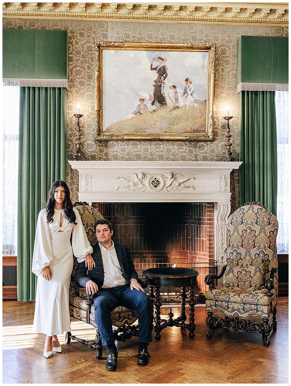 Man and woman sit together in front of fireplace during their Detroit Athletic Club engagement session